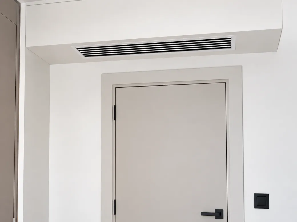 Grille de soufflage discrète d'une climatisation gainable au-dessus d'une porte